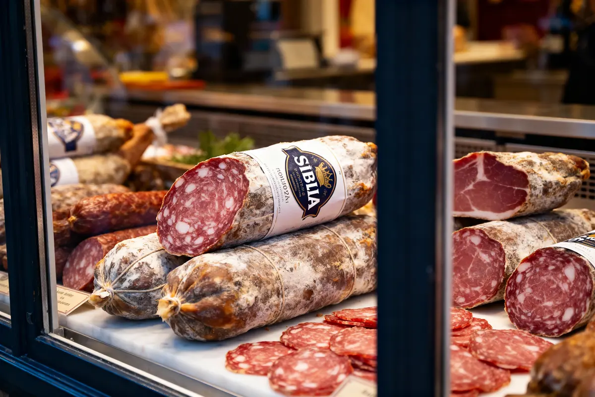Assortiment de saucissons et charcuteries exposés dans une vitrine de magasin, étiquetés "Siblia".