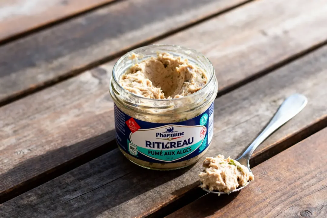 Pot de rillettes de la mer sur table en bois, avec cuillère contenant préparation fumée aux algues.