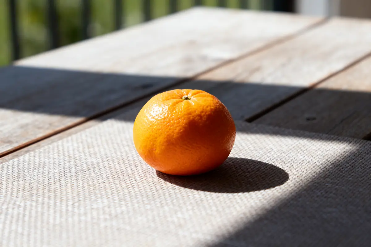 Clémentine posée sur une table en bois éclairée par le soleil calories d'une clémentine