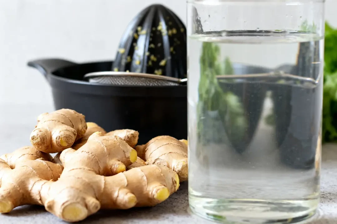 Verres d'eau, racines de gingembre, presse pour recette de jus de gingembre maison